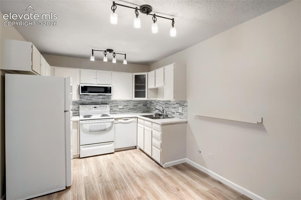 Image 6 of 27: Kitchen featuring wood-finish flooring and white cabinetry