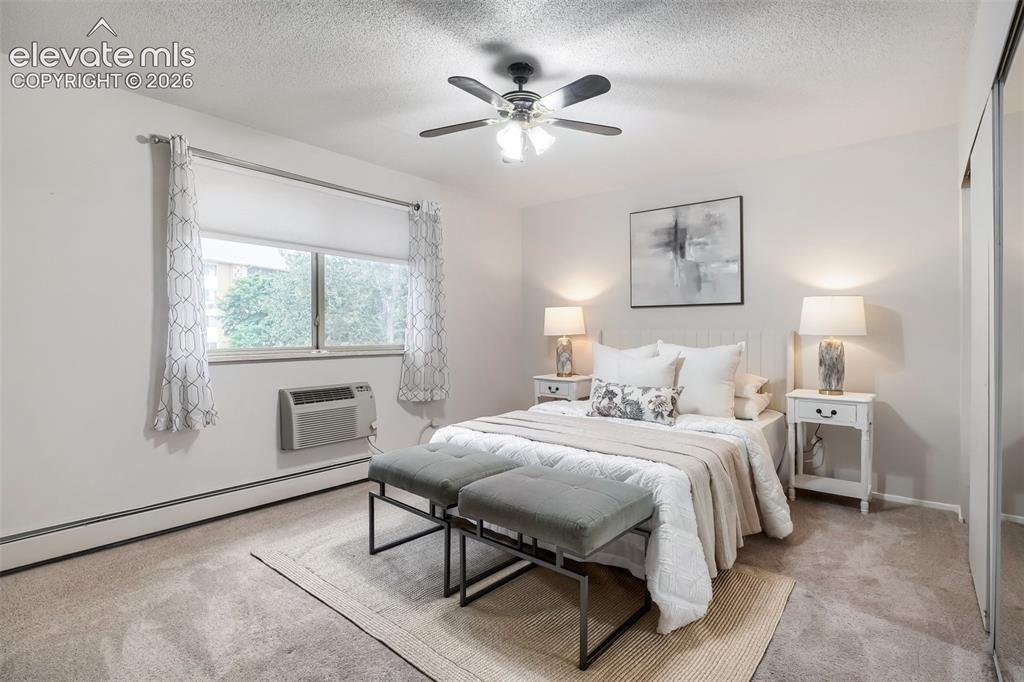 Image 7 of 27: Carpeted room with a ceiling fan, two windows, baseboard heating, and an in