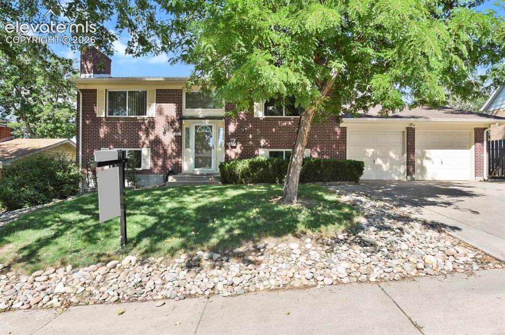 Image 1 of 31: Brick Colonial home featuring a mature tree-lined front yard with establish