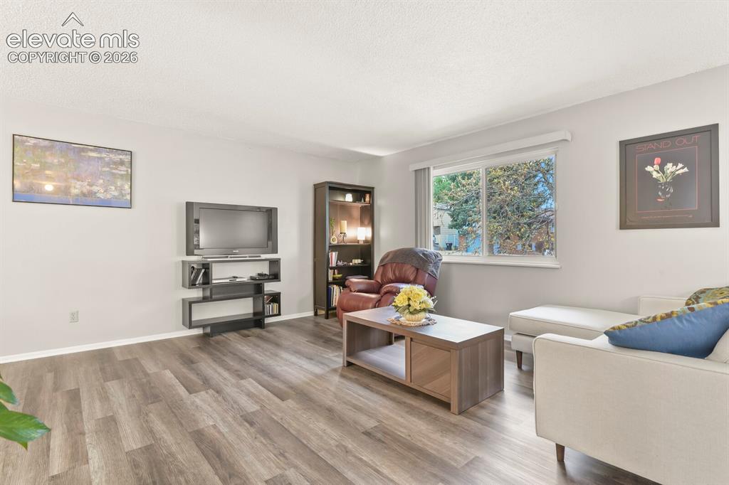 Image 2 of 31: Spacious living area featuring wood-finish flooring, light neutral wall ton