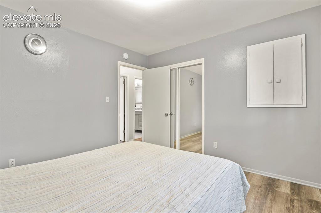Image 20 of 39: Bedroom featuring light gray wall paint, wood-finish flooring, and a built-