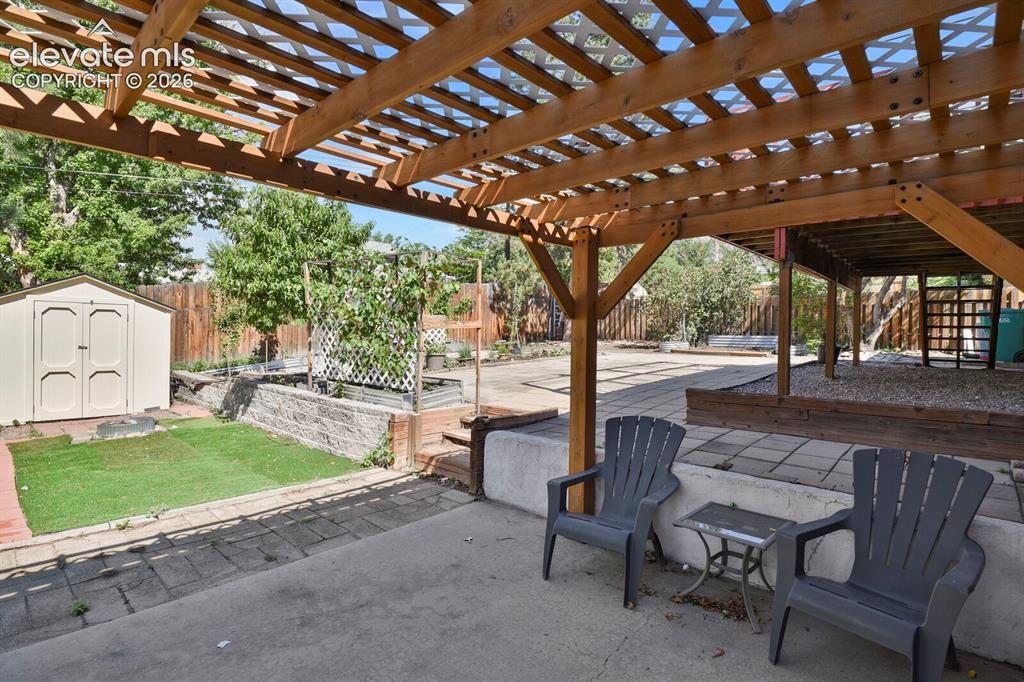 Image 20 of 31: Expansive covered patio with lattice pergola overhead, providing dappled sh