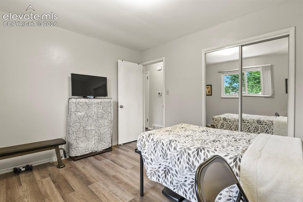 Image 22 of 39: Bedroom featuring wood-finish flooring, light-colored walls, and a ceiling-