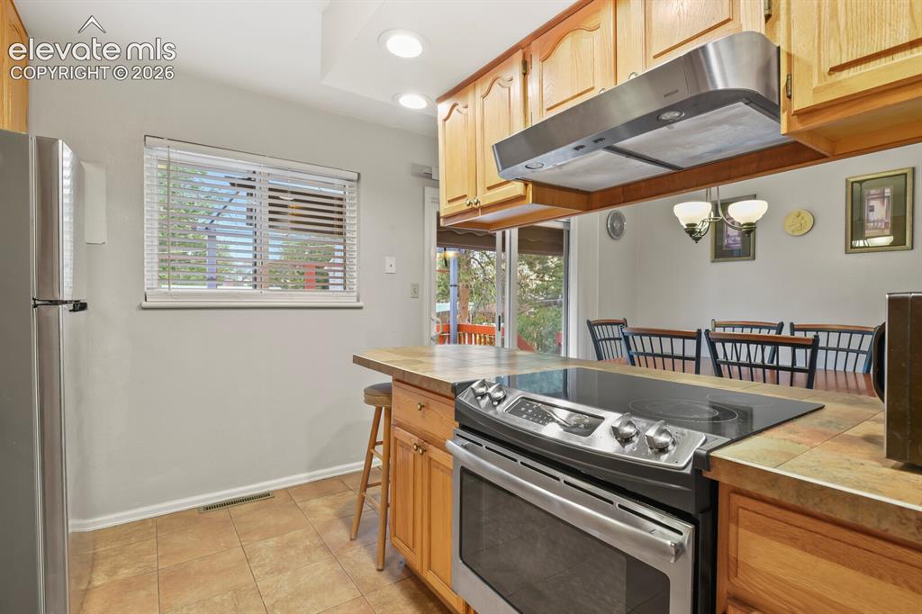 Image 22 of 31: Kitchen featuring a stainless steel range with a flat cooktop, wood cabinet