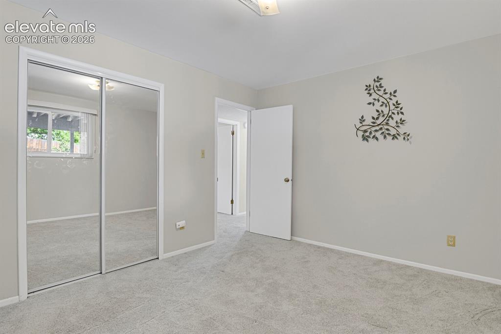 Image 24 of 31: Spacious bedroom featuring neutral carpeting, mirrored sliding closet doors