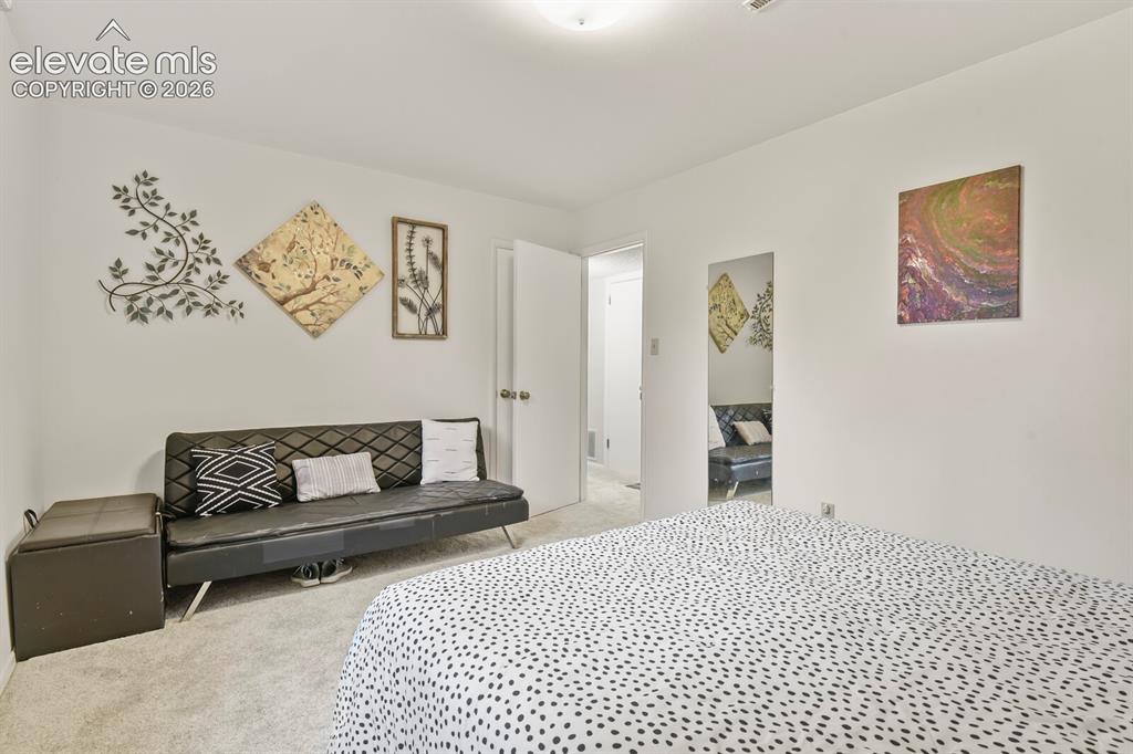Image 27 of 39: Carpeted room with white walls, a visible doorway, and a ceiling light fixt