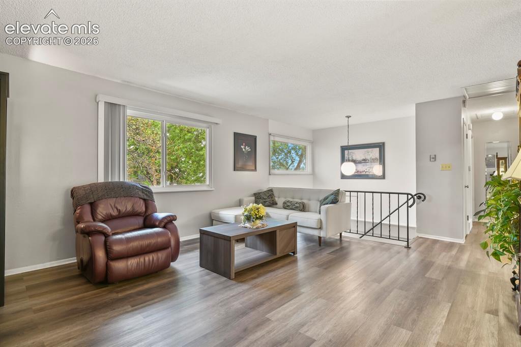 Image 3 of 31: Spacious living area featuring wood-finish flooring, light grey wall tones,