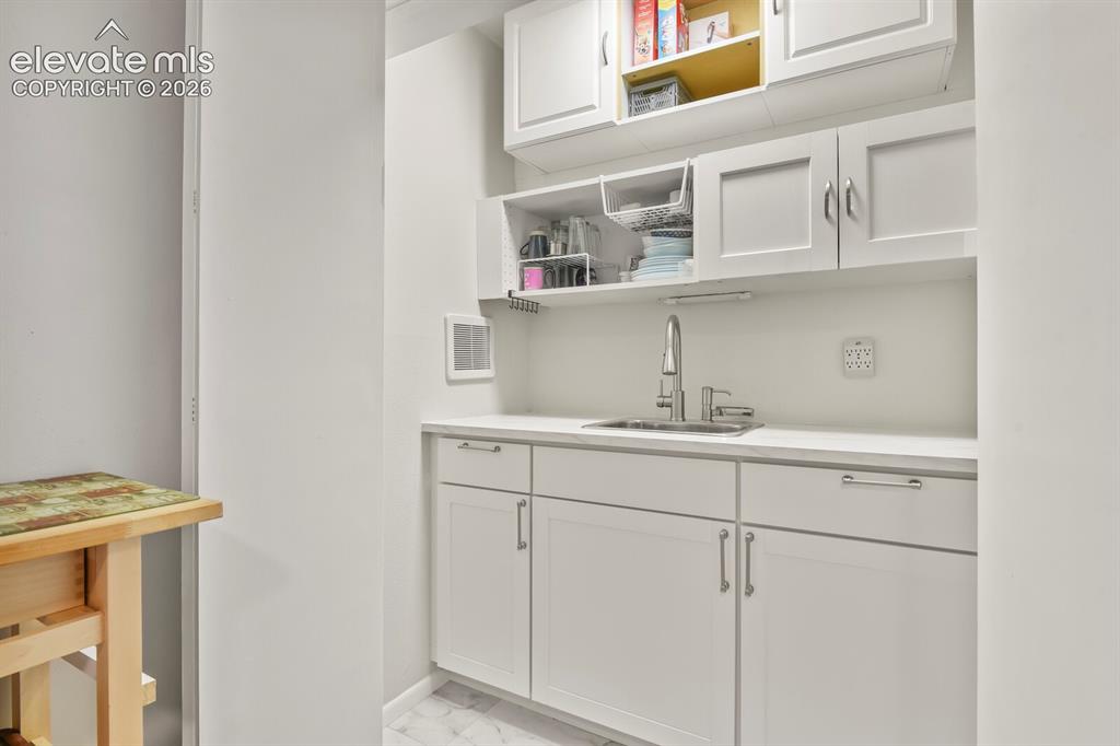 Image 30 of 39: White cabinetry with chrome hardware, an undermount sink, and a high-arc fa