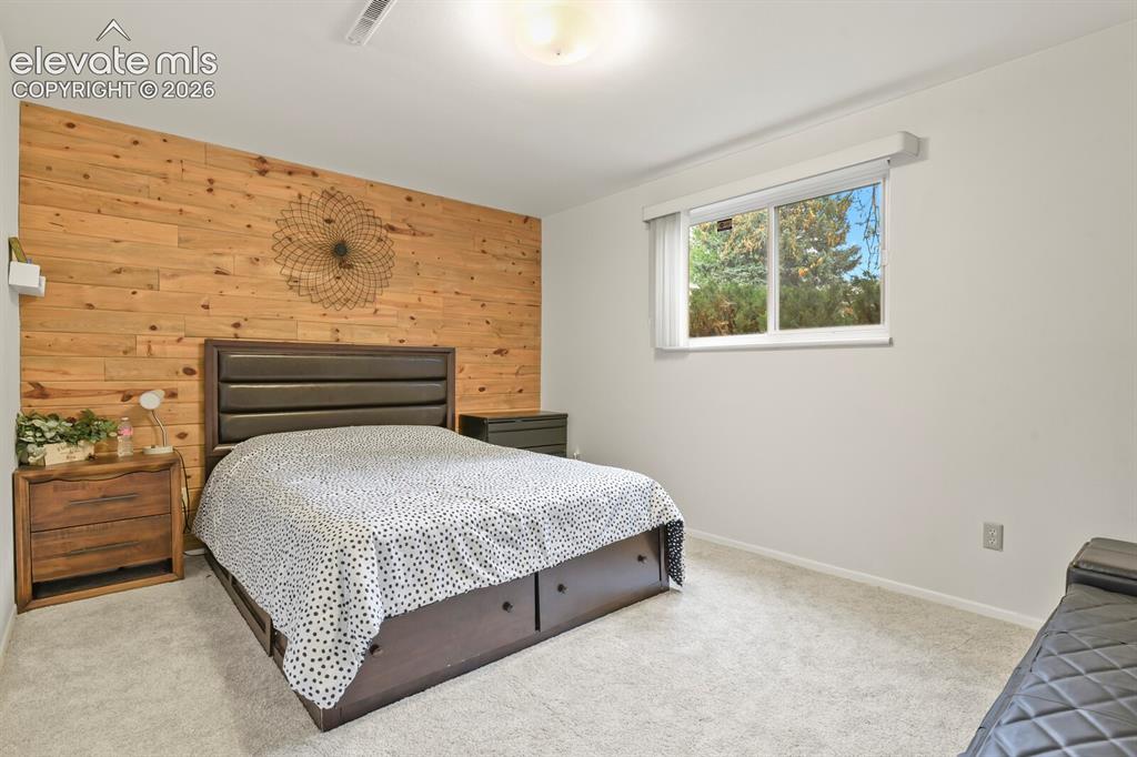 Image 33 of 39: Bedroom featuring a prominent wood plank accent wall, light-colored carpet,