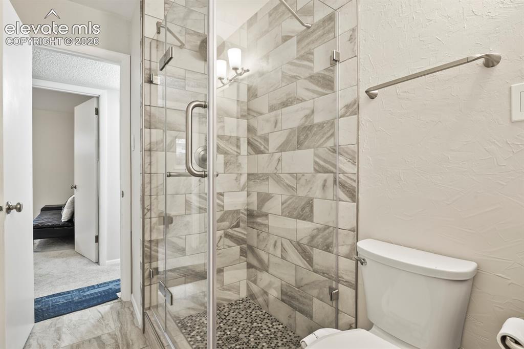 Image 36 of 39: Walk-in shower featuring a glass enclosure, a tiled surround with varying s