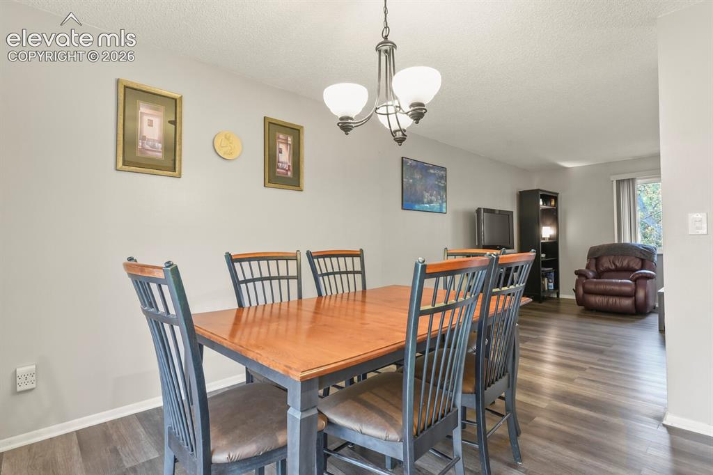 Image 4 of 31: Dining area featuring a classic chandelier with three opaque glass shades