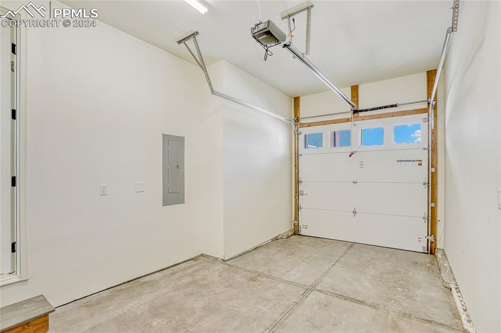 Image 15 of 24: Garage with a garage door opener and electric panel