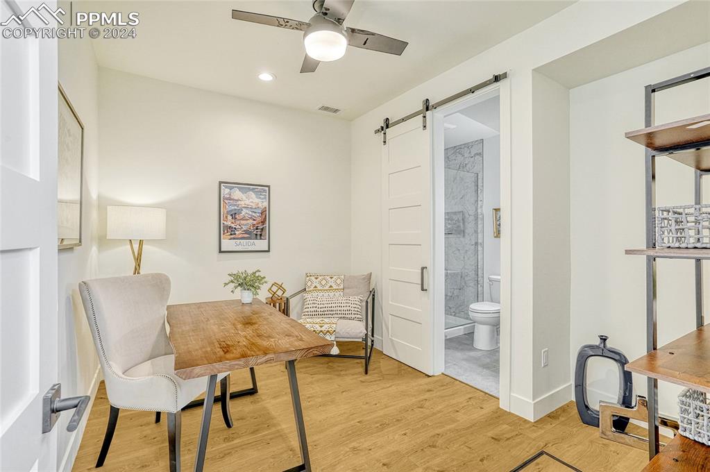 Image 2 of 24: Living area with a barn door, light hardwood / wood-style floors, and ceili