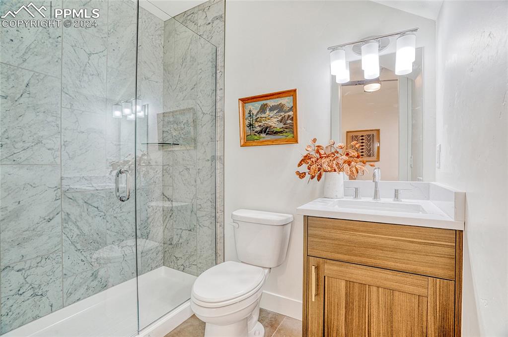 Image 3 of 24: Bathroom with tile patterned flooring, vanity, toilet, and a shower with sh