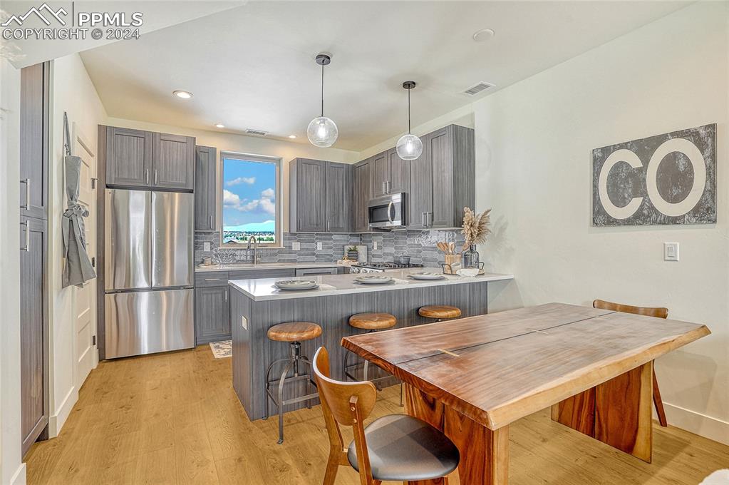 Image 7 of 24: Kitchen featuring pendant lighting, light wood-type flooring, appliances wi