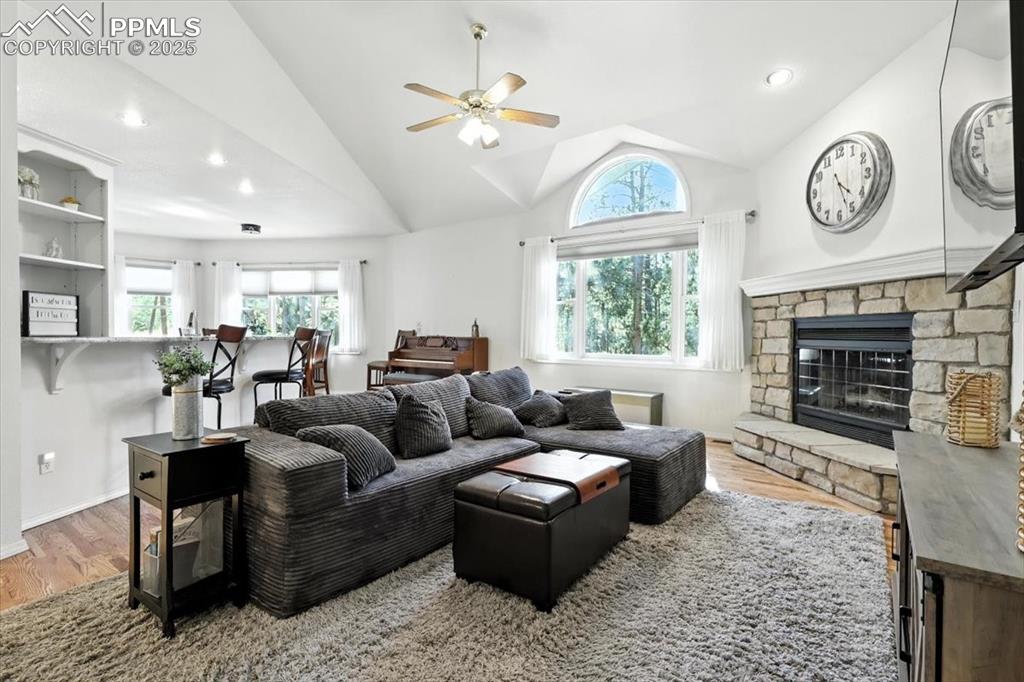 Image 10 of 45: Living area with wood finished floors, ceiling fan, lofted ceiling, a firep