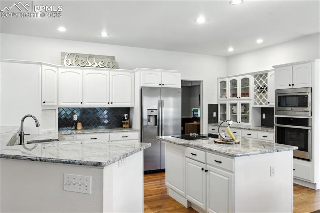 Image 12 of 45: Kitchen with stainless steel appliances, white cabinetry, light wood-style