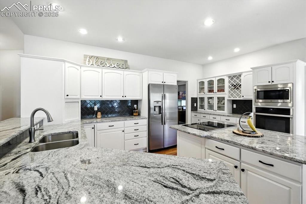 Image 14 of 45: Kitchen with appliances with stainless steel finishes, backsplash, white ca