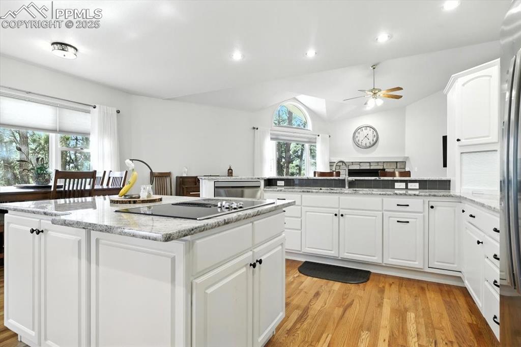 Image 16 of 45: Kitchen featuring black electric stovetop, a peninsula, ceiling fan, light