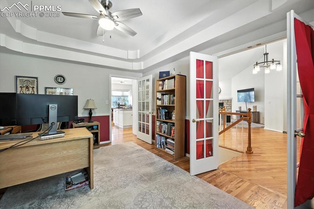Image 25 of 45: Home office featuring a raised ceiling, wood finished floors, ceiling fan,