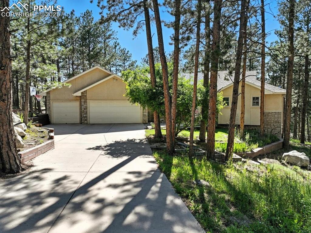 Image 3 of 45: Mid-century home with stone siding, stucco siding, concrete driveway, and a
