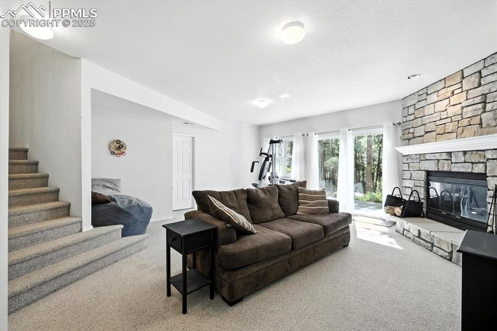Image 30 of 45: Living room with carpet flooring, stairway, and a fireplace