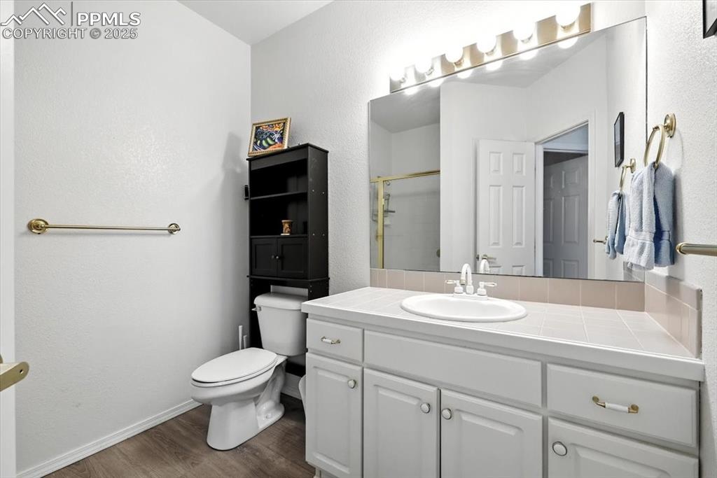 Image 35 of 45: Bathroom with wood finished floors, vanity, and a shower with door