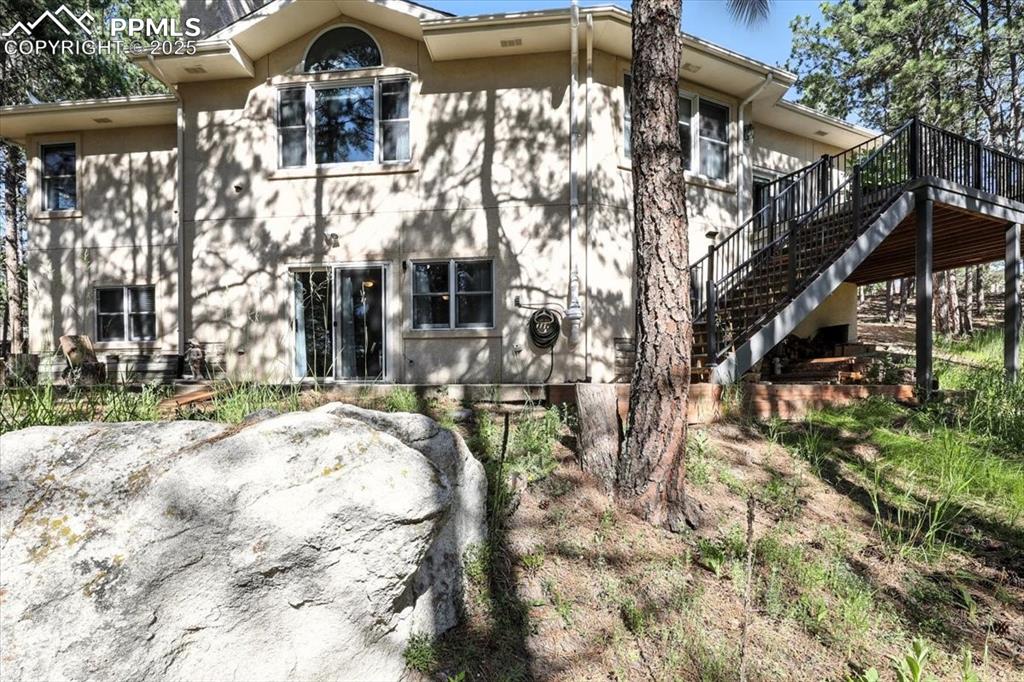 Image 43 of 45: View of front facade with stairs, a wooden deck, and stucco siding