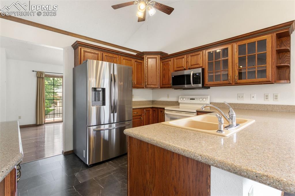 Image 12 of 30: Kitchen with appliances with stainless steel finishes, a ceiling fan, brown