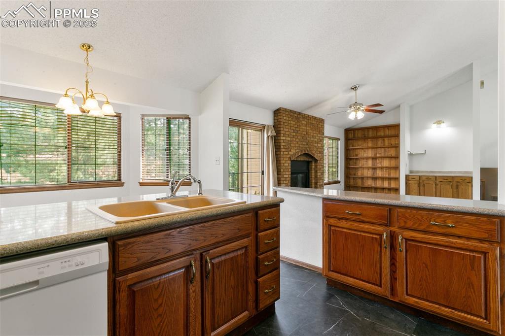 Image 13 of 30: Kitchen with vaulted ceiling, white dishwasher, a ceiling fan, a fireplace,