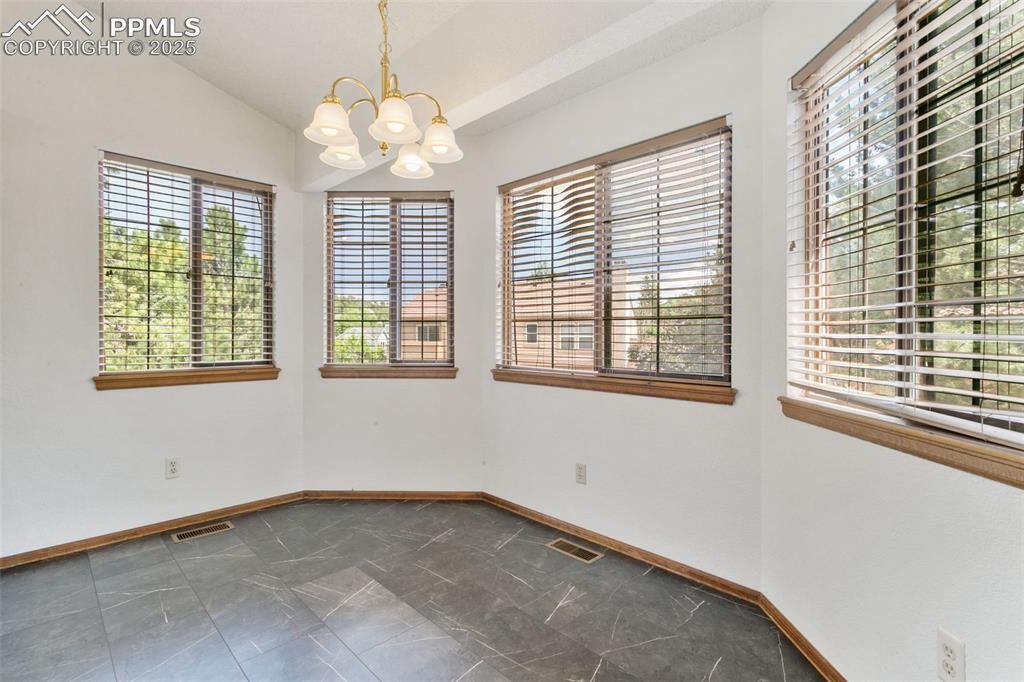 Image 14 of 30: Spare room featuring a chandelier, dark marble finish flooring, and lofted
