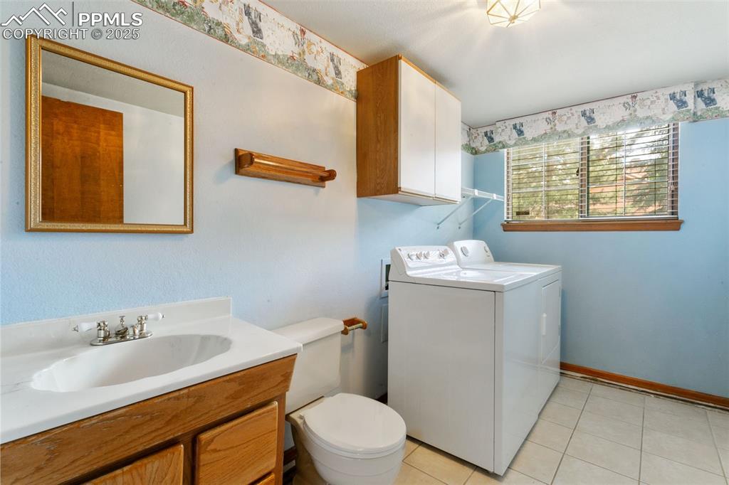Image 16 of 30: Bathroom featuring washing machine and clothes dryer, vanity, and tile patt