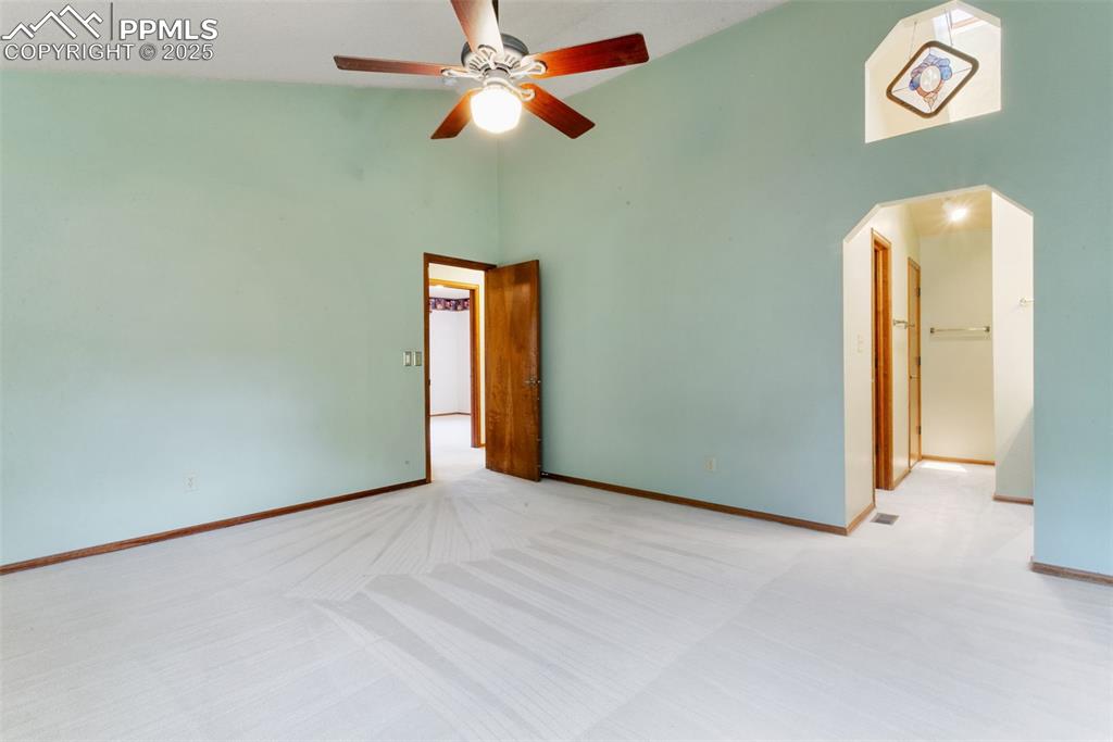 Image 17 of 30: Carpeted empty room with high vaulted ceiling and a ceiling fan