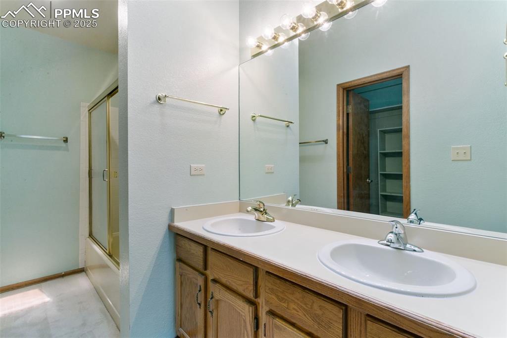 Image 19 of 30: Bathroom featuring double vanity and combined bath / shower with glass door