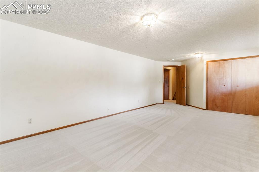 Image 26 of 30: Unfurnished bedroom with a textured ceiling, a closet, and light colored ca