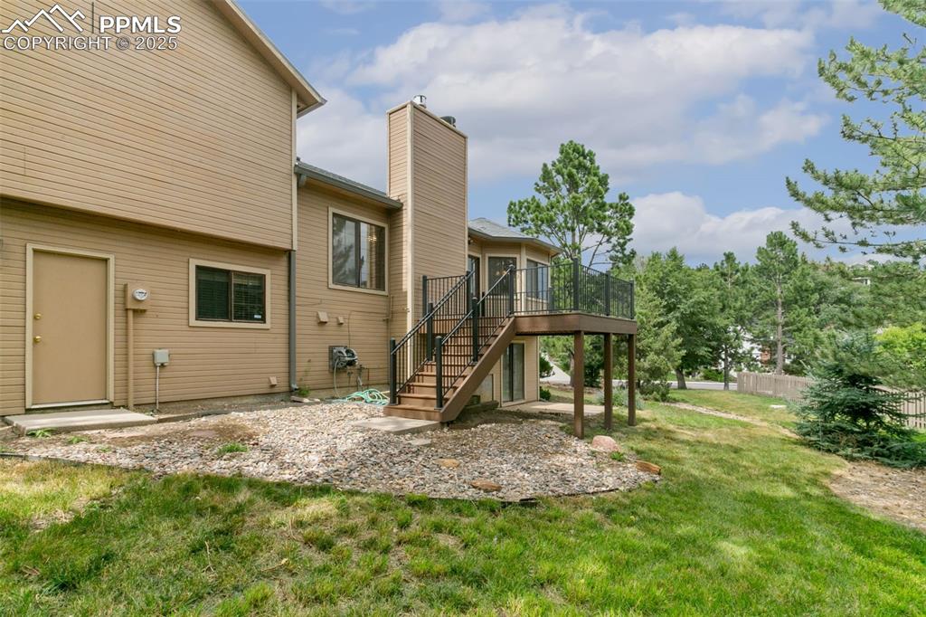 Image 28 of 30: Back of property featuring stairway, a deck, a chimney, and a yard