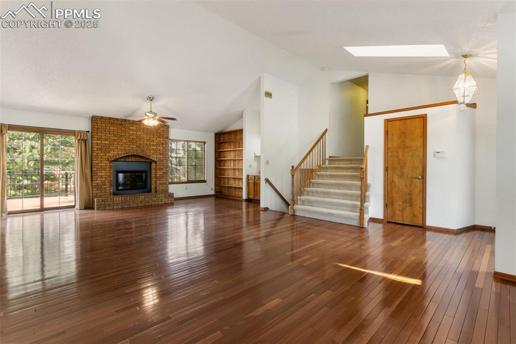 Image 5 of 30: Unfurnished living room with ceiling fan, plenty of natural light, stairway