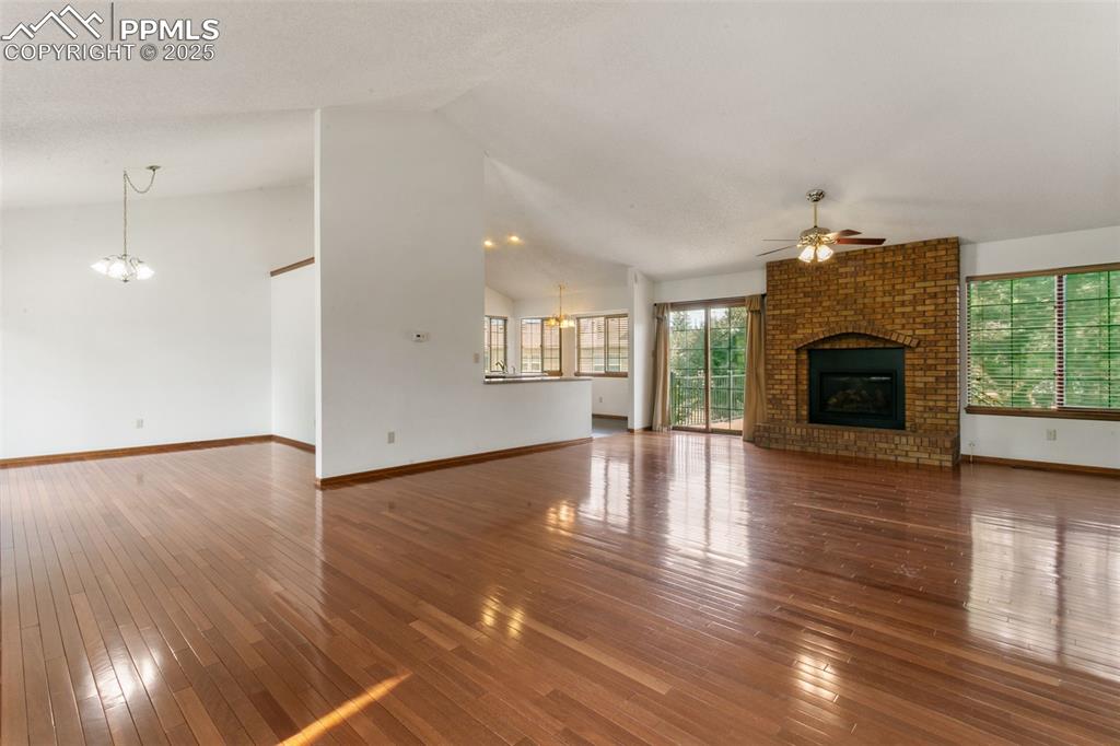 Image 6 of 30: Unfurnished living room featuring a ceiling fan, a chandelier, a brick fire
