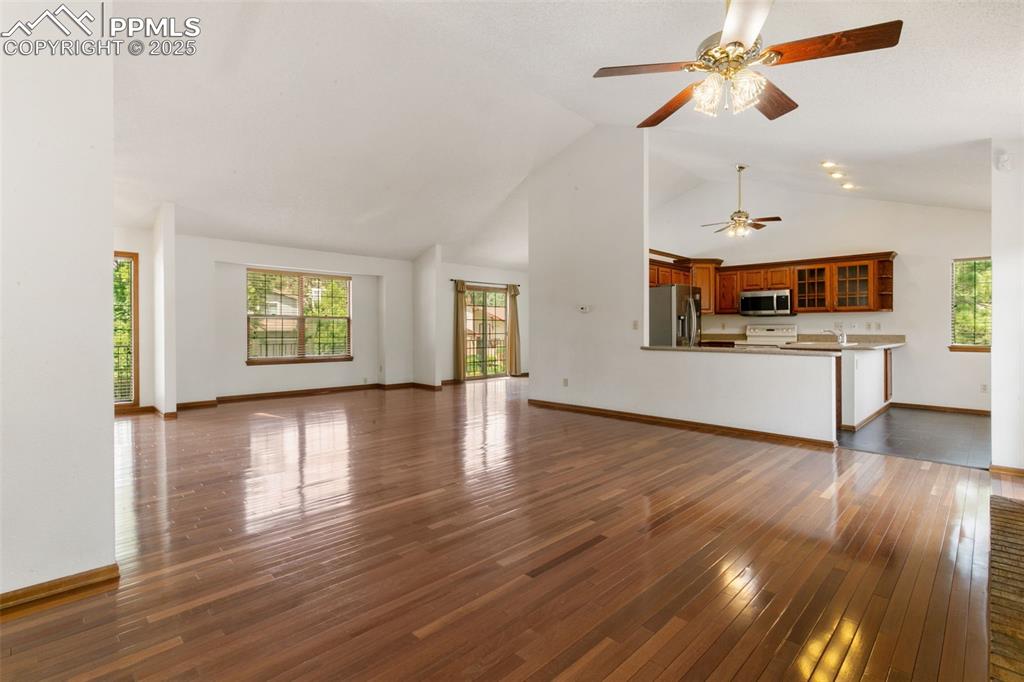 Image 8 of 30: Unfurnished living room with ceiling fan, dark wood-style flooring, plenty