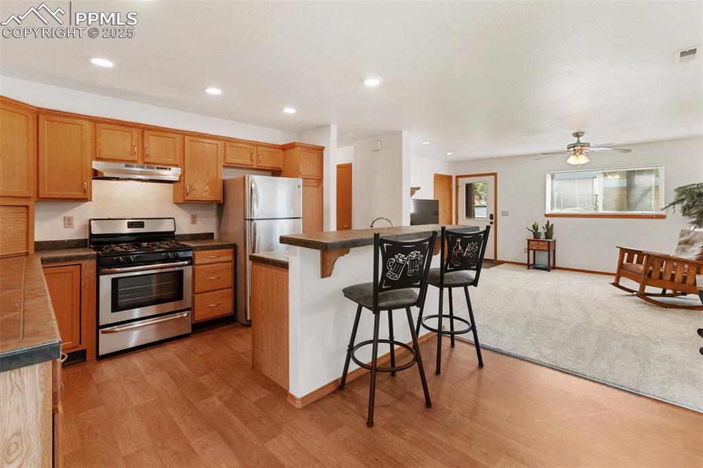 Image 10 of 30: Kitchen featuring a breakfast bar area, stainless steel appliances, an isla