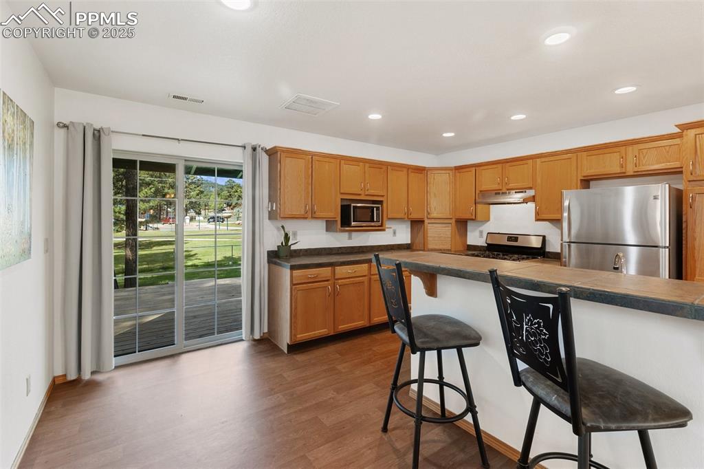 Image 11 of 30: Kitchen featuring a kitchen breakfast bar, appliances with stainless steel 