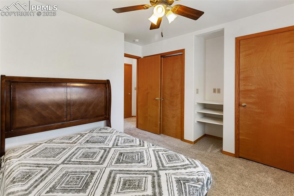 Image 13 of 30: Unfurnished bedroom with light carpet, a ceiling fan, two closets, and an o