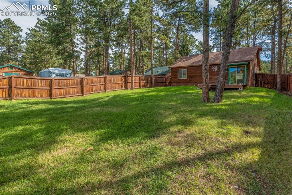 Image 20 of 30: Fenced backyard with view of wooded area