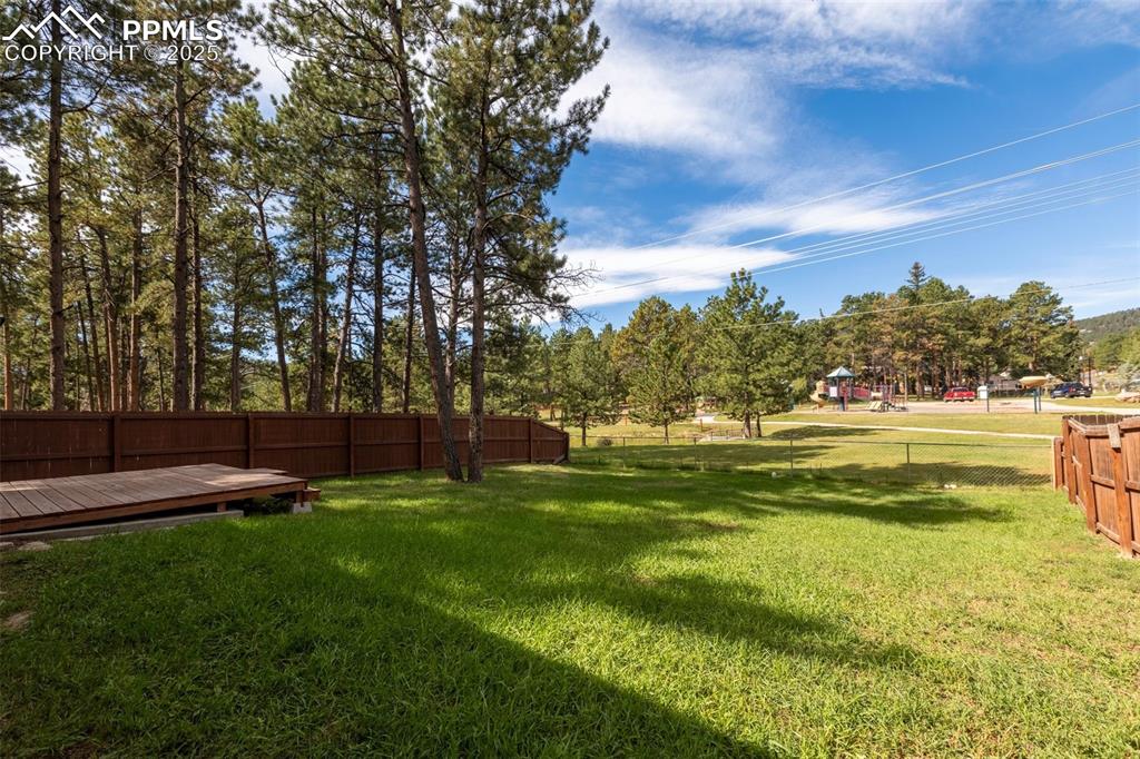 Image 21 of 30: Fenced backyard with a deck