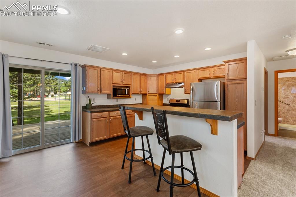 Image 22 of 30: Kitchen featuring a kitchen breakfast bar, dark countertops, stainless stee