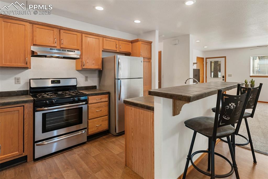 Image 23 of 30: Kitchen with appliances with stainless steel finishes, a kitchen bar, under