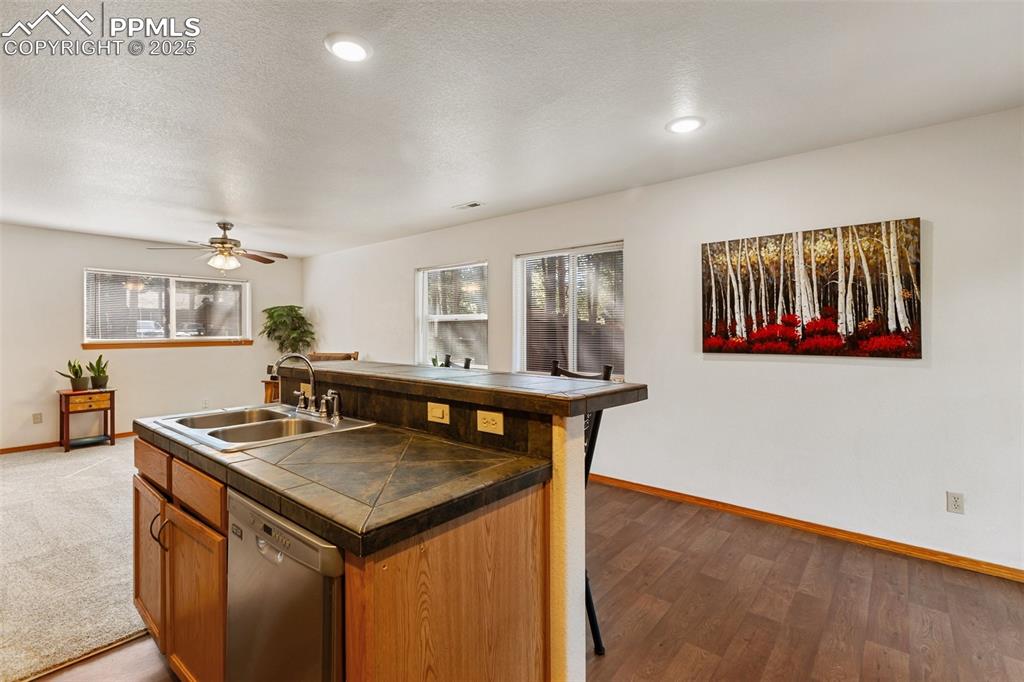 Image 24 of 30: Kitchen featuring stainless steel dishwasher, a center island with sink, da