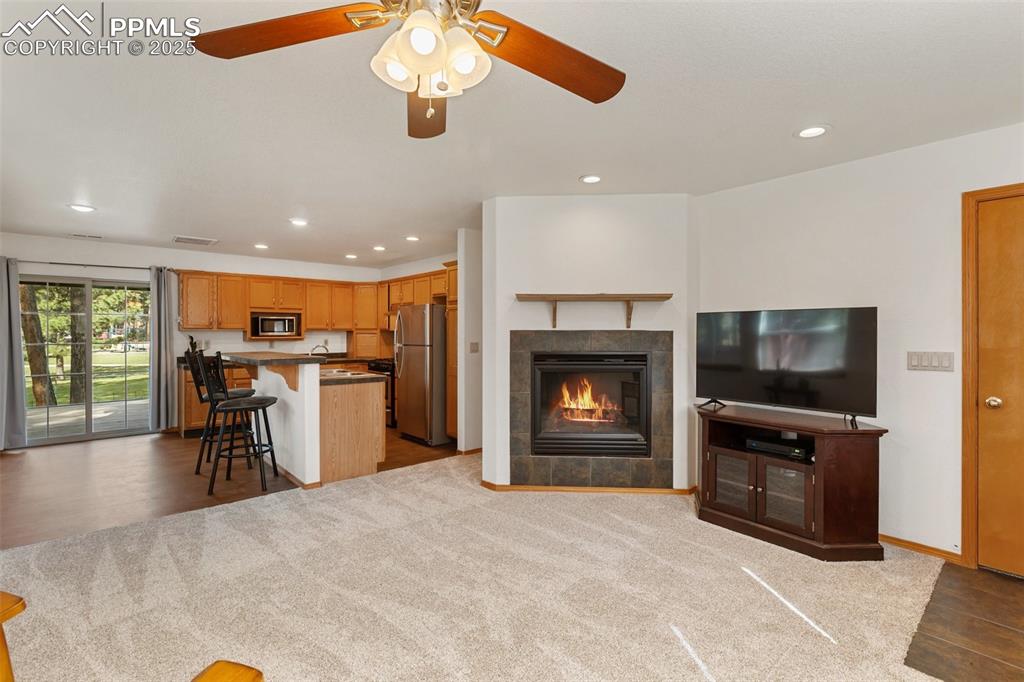 Image 26 of 30: Living room with recessed lighting, a fireplace, ceiling fan, dark wood-sty