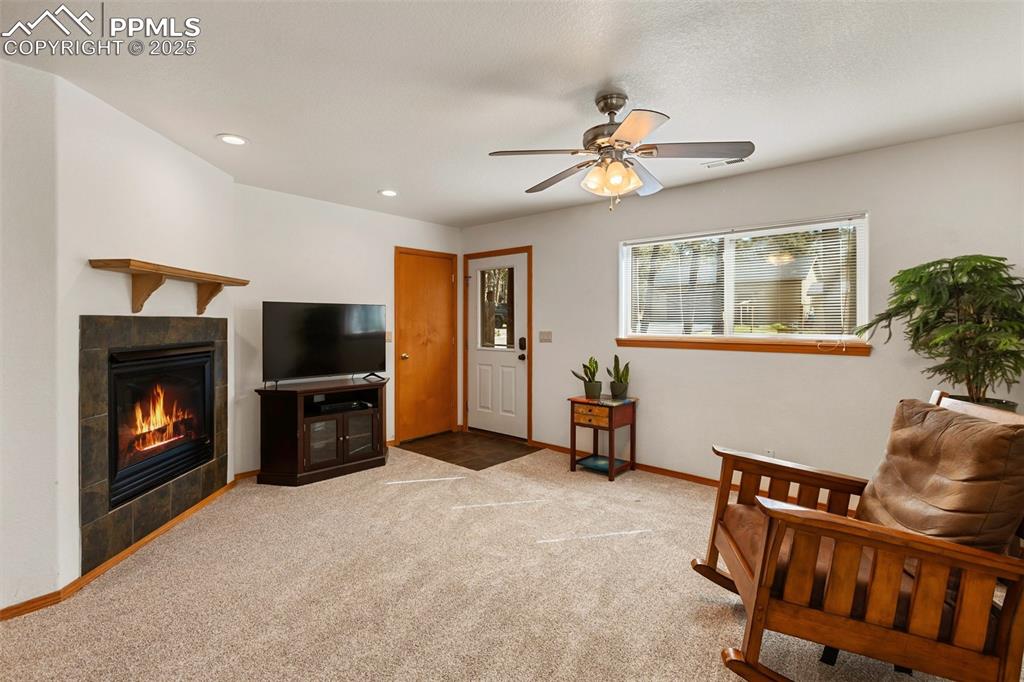 Image 6 of 30: Living area featuring a tile fireplace, light colored carpet, recessed ligh