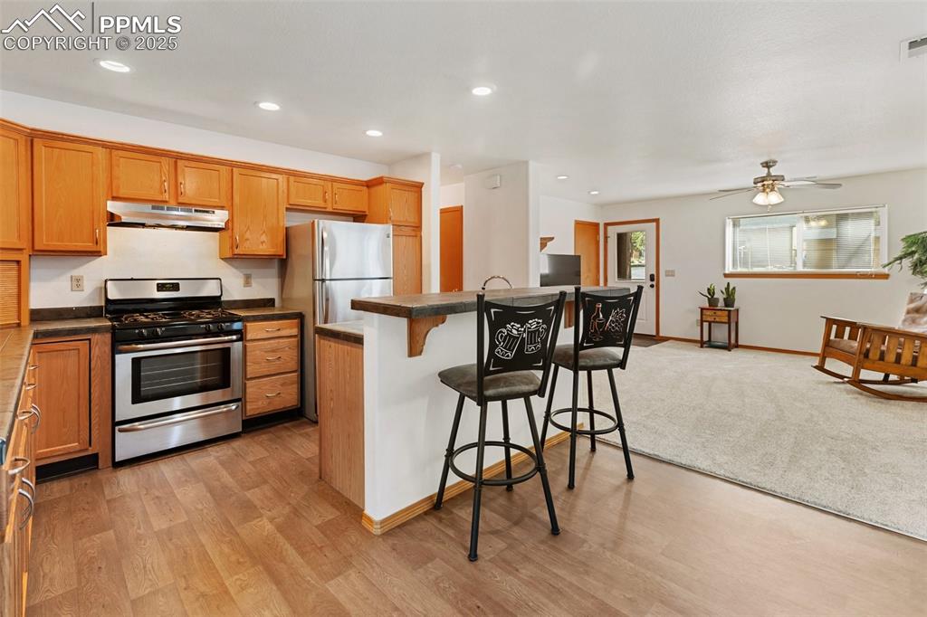 Image 7 of 30: Open kitchen with gas range and breakfast bar island.